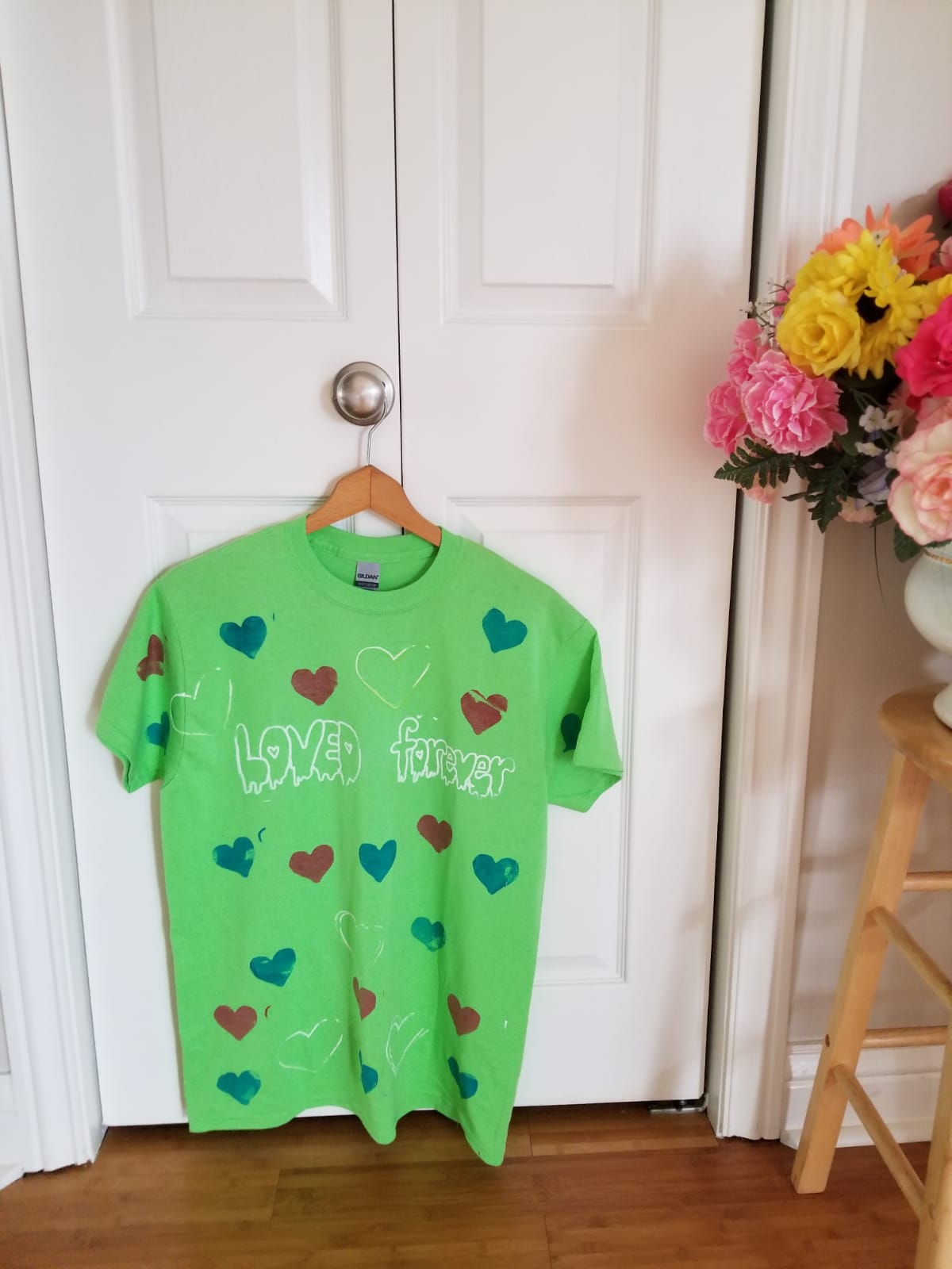 Hang on door handle a green shirt with printed hearts with text, Loved forever