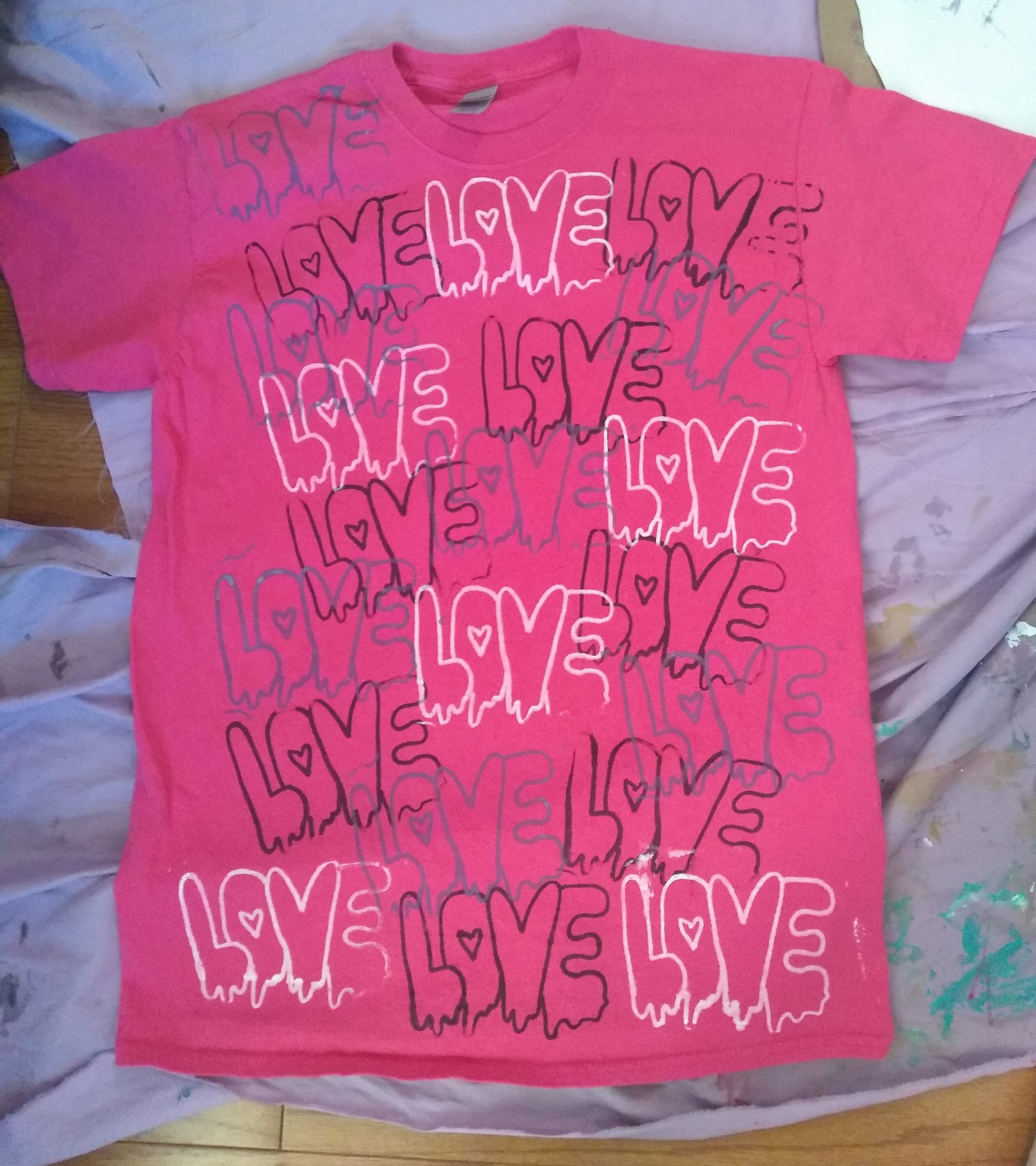Pink tshirt lay flat with white and black text reads Love