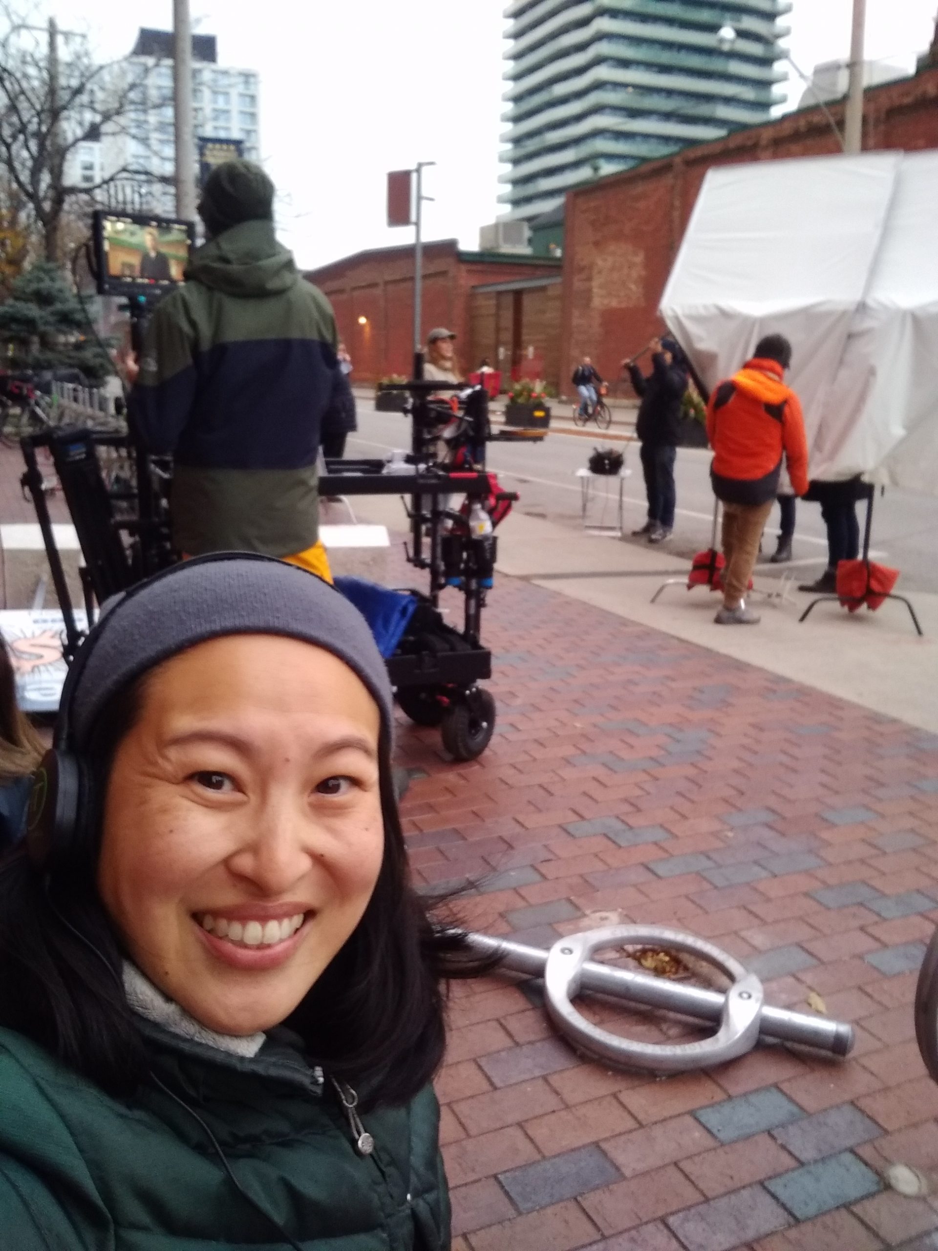 Amanda smiles while outside in winter clothing behind the scenes of a film shoot