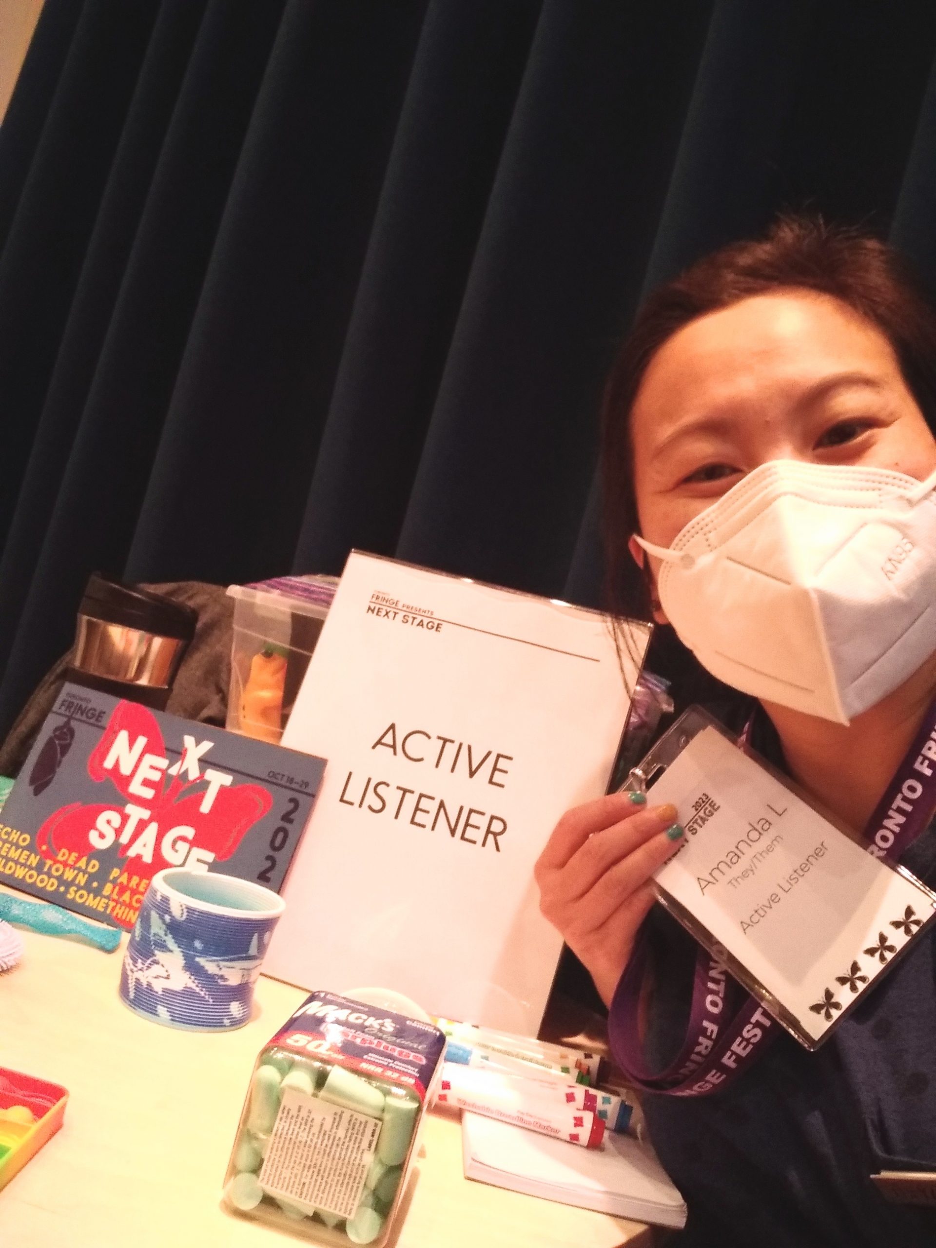 Amanda in a mask smiling in front of Active Listener table